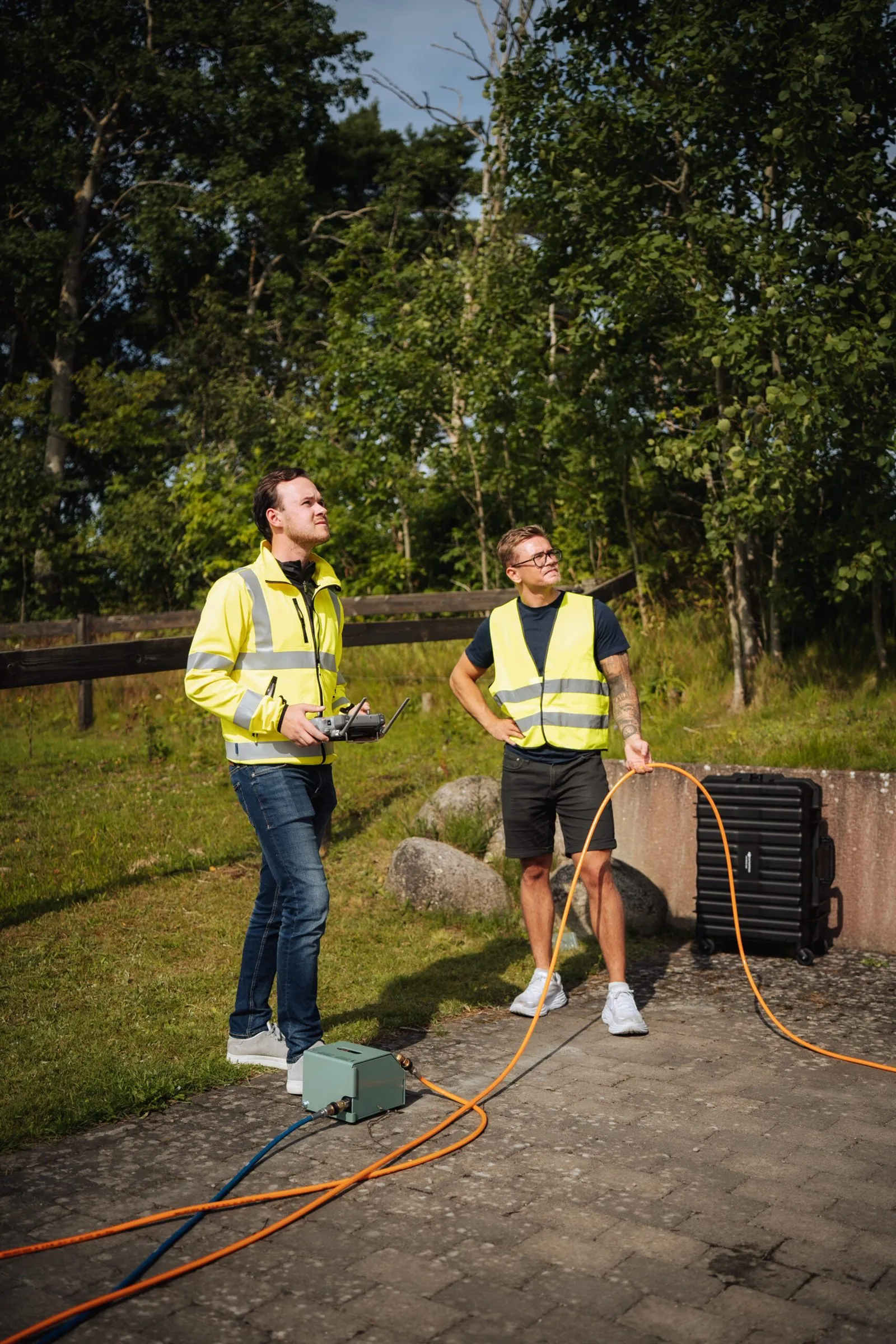Två av NordTvätts tekniker styr drönaren från marken under en fasadtvätt