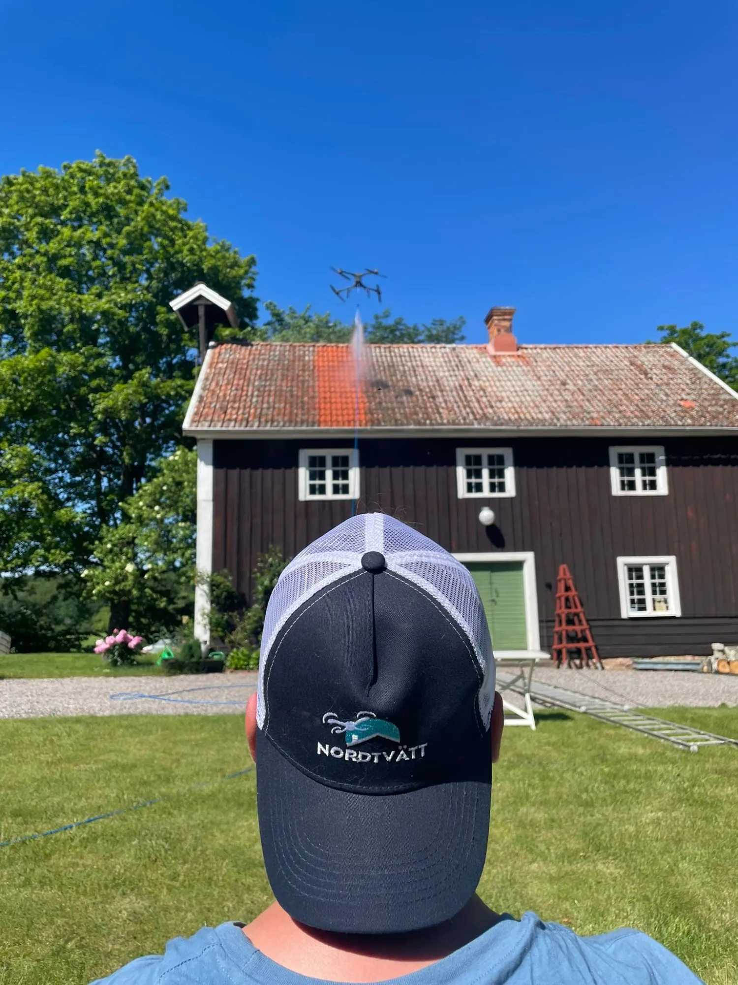 Drönaren högtryckstvättar ett tegeltak – det tvättade stråket syns direkt